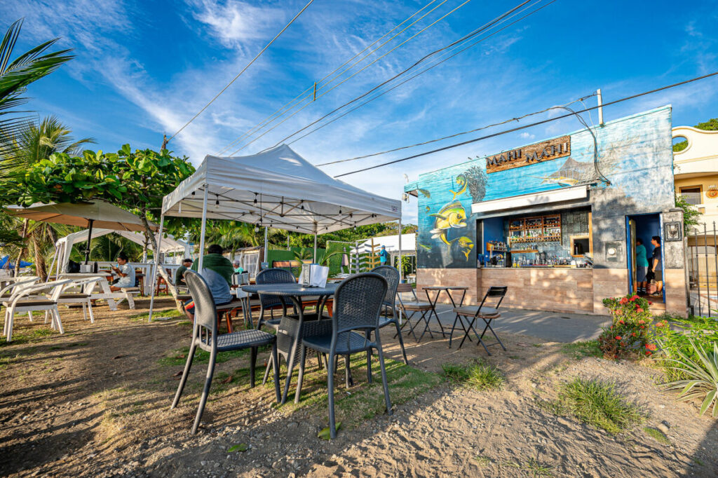 Mahi Mahi beach bar and restaurant with outdoor seating, shade canopy and painted fish mural near Casa Rio Mar in Jaco Beach, Costa Rica